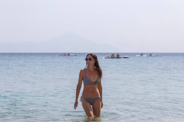 Attractive female tourist getting out from sea water after swimming