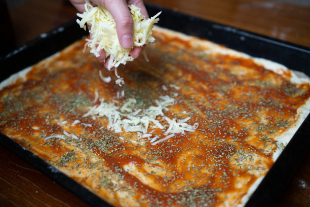 Close up of woman's hand adding cheese on pizza