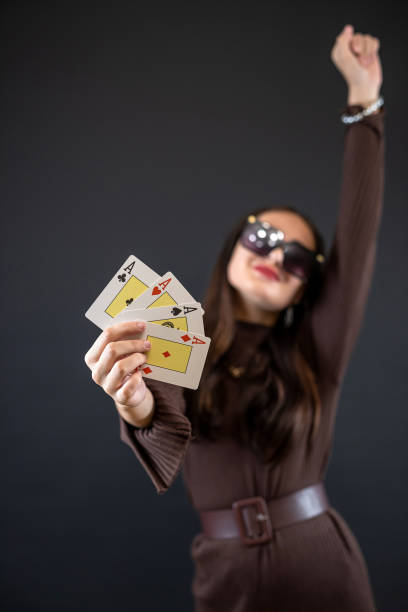 Young pretty woman with playing cards ace posign isolated on black background. Gambling concept