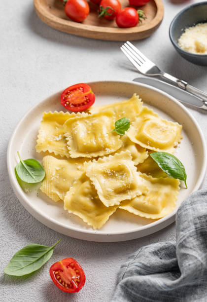istock Homemade ravioli pasta with cheese, tomatoes and basil in a plate on a light  background with  fork and napkin. 2189078795