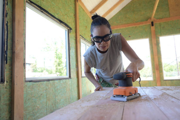 A woman sanding a wooden wall panel before installing it.