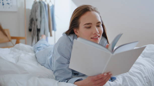 istock Closeup woman looking book lying comfortable home bed. Student absorbed in novel 2189079291