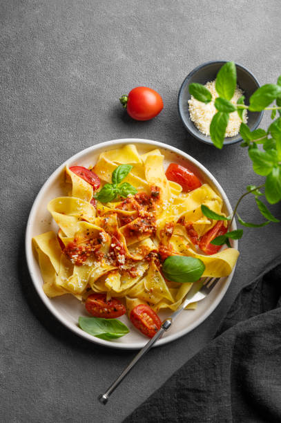 istock Tagliatelle pasta with tomato sauce, basil and parmesan cheese in a plate on a dark background. 2189081178