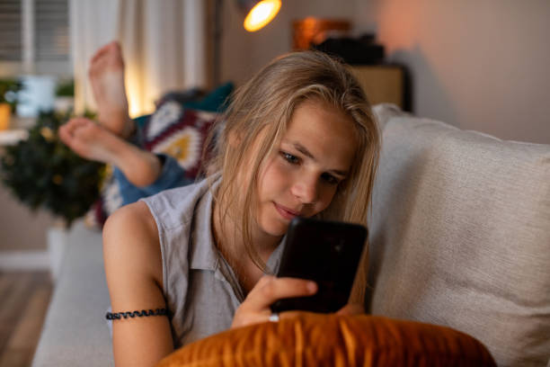 istock A young individual is immersed in using a smartphone while seated comfortably at home 2189084783