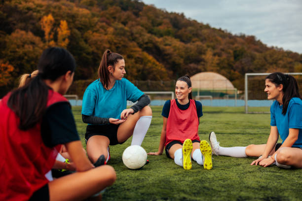 istock Joyful soccer girls sitting on pitch. 2189087075