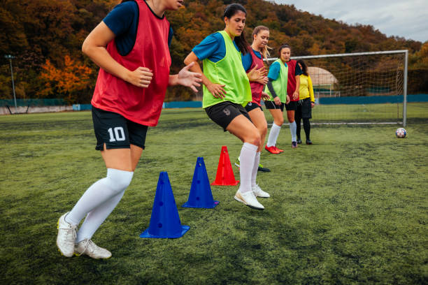A group of female soccer players are in the field exercising endurance with cones.