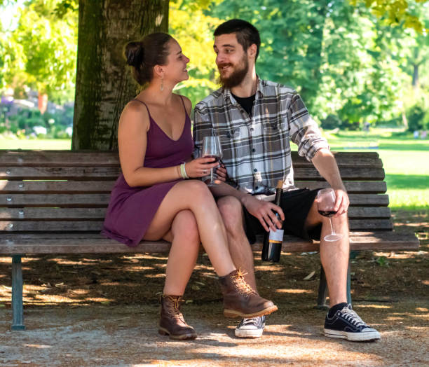 istock Happy couple chilling on bench in park, drinking wine 2189087343