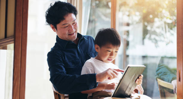 istock Education, study or tablet with father and son on chair in home for child development or learning. Japanese family, reading or technology with single parent man and boy in apartment for search 2189091882
