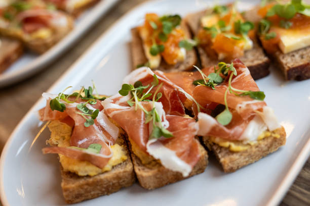 Bruschetta with sourdough bread, scrambled eggs and prosciutto Bruschetta with sourdough bread, scrambled eggs and prosciutto - Buenos Aires - Argentina prosciutto brie stock pictures, royalty-free photos & images