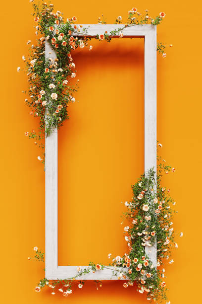 istock White wooden frame decorated with pink roses on orange background with copy space. Spring concept design. 2189095359