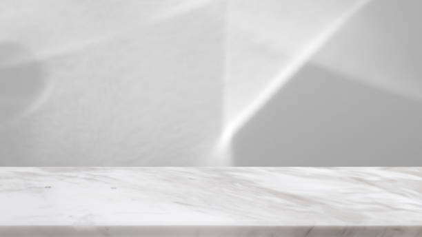 Marble table top with abstract shadow drop on white wall background for mockup product display