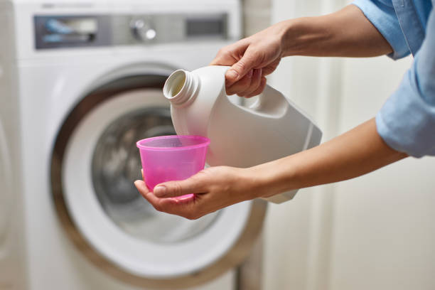 Woman pours liquid laundry detergent into plastic cap