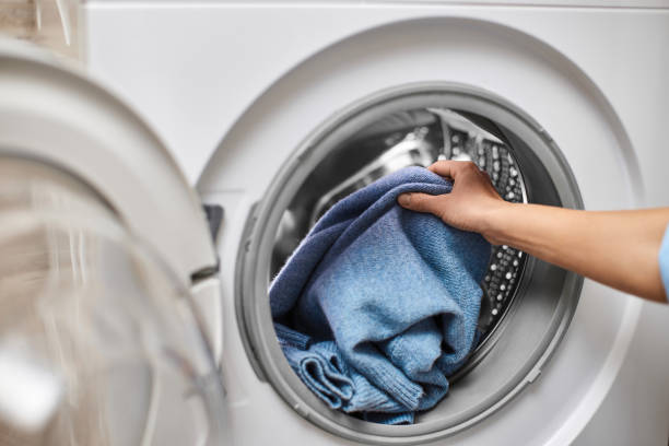 istock Woman putting clothes into the washing machine 2189097919