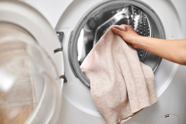 istock Woman putting clothes into the washing machine 2189097932