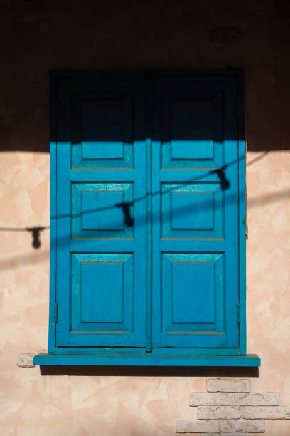 istock Wooden Window Half Covered in Shadow on Old Grunge Plaster Wall. 2189113096