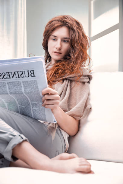 istock Young woman reading business newspaper on the sofa 2189125739
