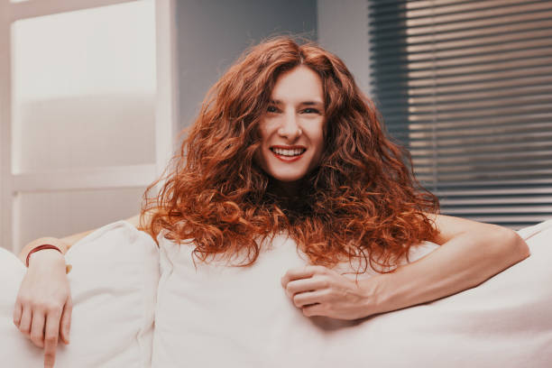 istock Happy redhead woman relaxing on comfortable sofa at home 2189125856
