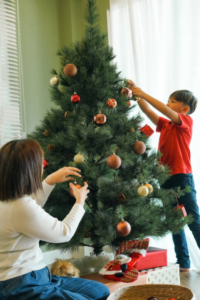 istock Young boy decorates a Christmas tree with mother at home. 2189126094