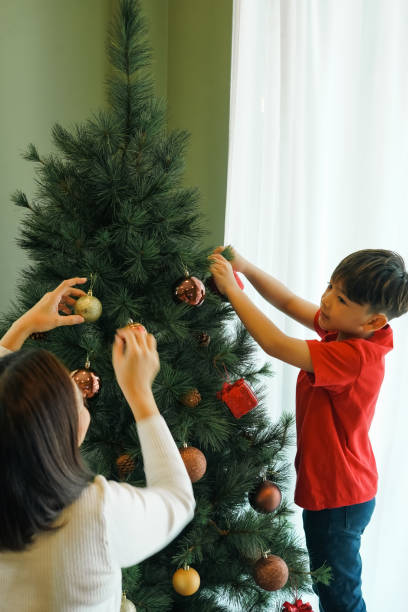 istock Young boy decorates a Christmas tree with mother at home. 2189126099