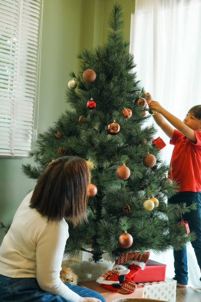 istock Young boy decorates a Christmas tree with mother at home. 2189126104