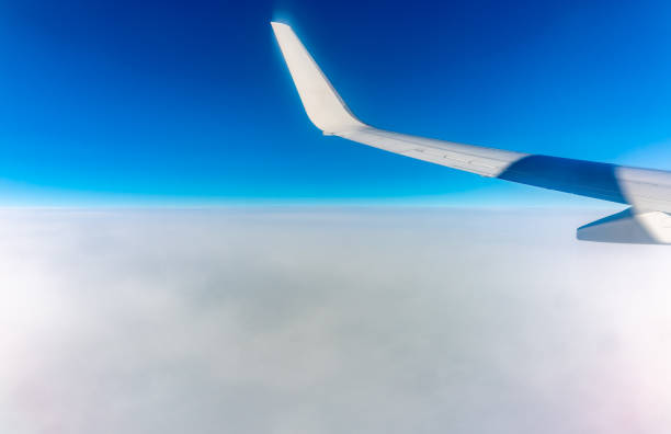 View from the airplane window at a beautiful cloudy sky and the airplane wing. Earth and sky as seen through window of an airplane.