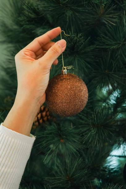 istock Hands hanging golden ball decorations on a Christmas tree 2189127791