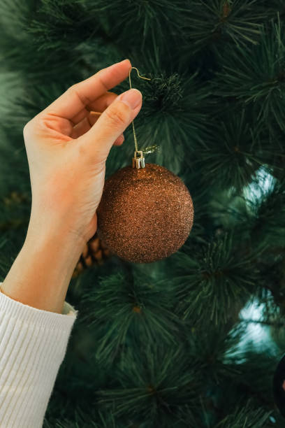 istock Hands hanging golden ball decorations on a Christmas tree 2189127792