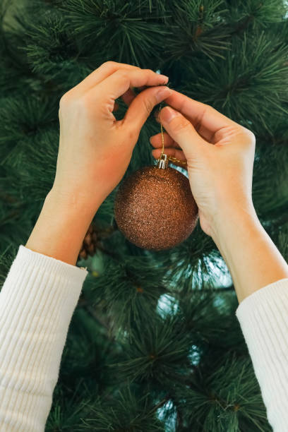 istock Hands hanging golden ball decorations on a Christmas tree 2189127795