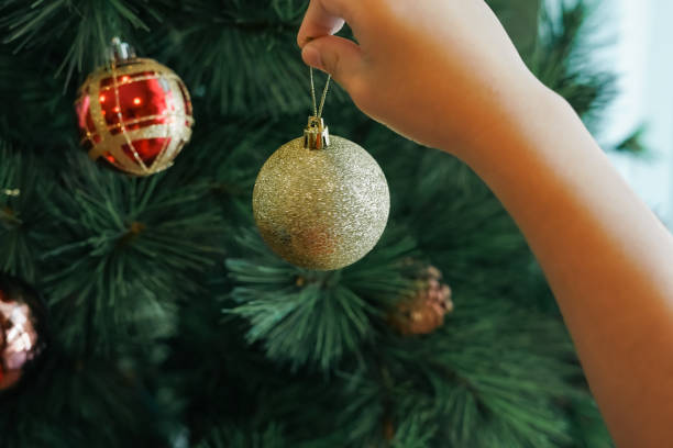 istock Hands hanging golden ball decorations on a Christmas tree 2189127802