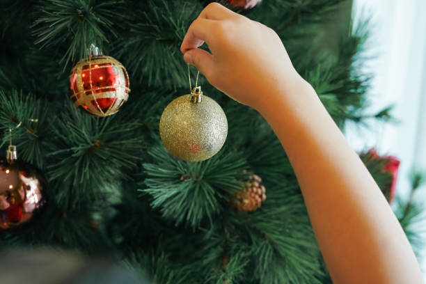 istock Hands hanging golden ball decorations on a Christmas tree 2189127806