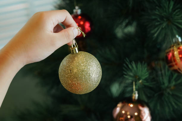 istock Hands hanging golden ball decorations on a Christmas tree 2189127820
