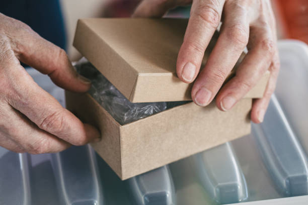istock Elderly female hands open a small cardboard box, close-up, selective focus. 2189131702