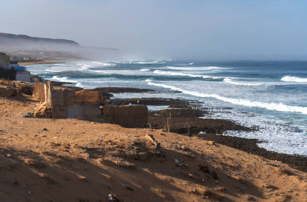 istock Poor Moroccan fishing village, Atlantic Ocean shore, Simple structures and sandy terrain, waves crashing on coastline 2189132835