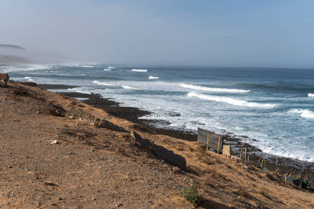 istock Poor Moroccan fishing village, Atlantic Ocean shore, Simple structures and sandy terrain, waves crashing on coastline 2189133111