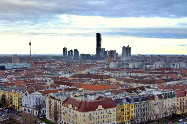 Aerial view of Vienna, Austria, showcasing the city's modern skyline including the skyscrapers of Donau City, with the Danube River and the lush greenery of the Danube Island (Donauinsel) in the foreground. Clear, sunny day. Vienna in Austria, Europe.