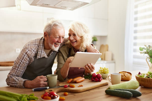 istock Happy senior couple using touchpad while preparing food in the kitchen. 2189139448