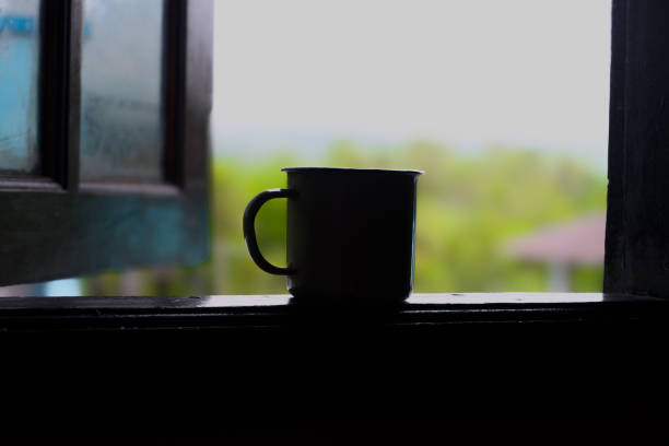 Silhouette of a cup in a window frame with a beautiful view in the background