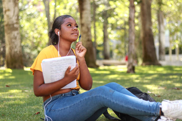 istock A reflexive black woman student sitting on the grass in a park 2189143969