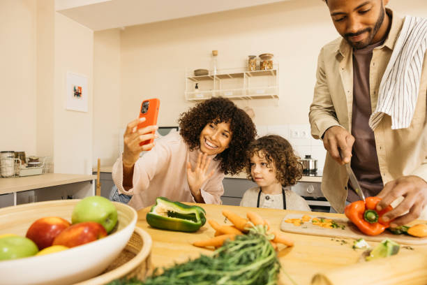 istock Happy family using an smartphone for a video call while preparing a healthy meal at home. 2189145283