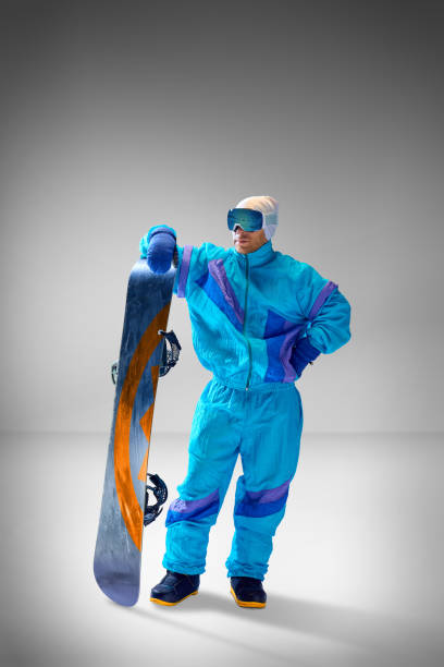Young man, athlete dressed in blue retro-inspired suit, against grey studio background. Ideal for extreme sports themes.