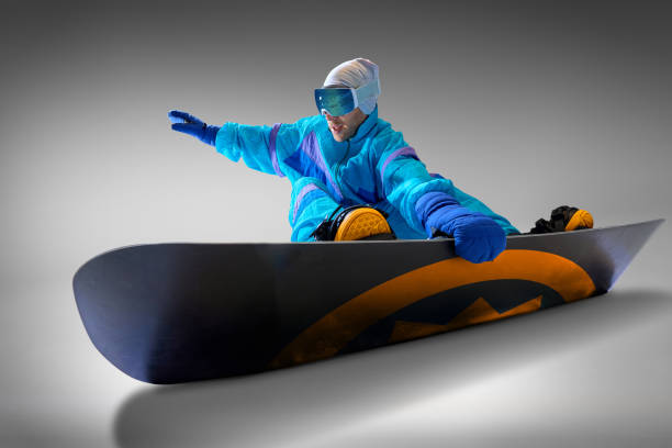 istock Snowboarder dressed retro blue jumpsuit poised for action against grey studio background, capturing charm of classic style in winter sports. 2189147648