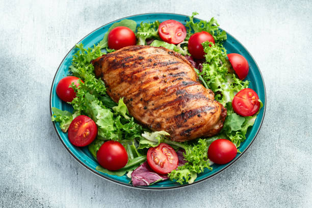 istock Grilled chicken breast ( fillet ) with lattuce salad and cherry tomatoes . Top view 2189147668