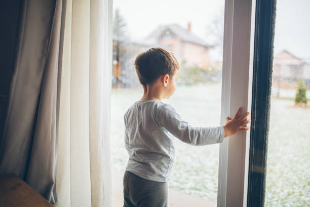 istock Little boy looking outside through the window, bad weather, quarantine 2189150267