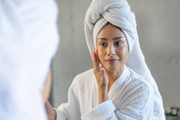 istock Young woman applying cream on face after shower 2189150320