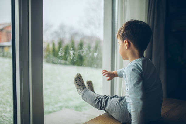 istock Little boy looking outside through the window, bad weather, quarantine 2189150384