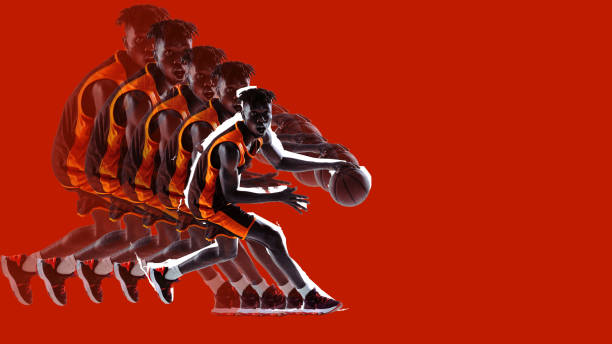 istock Dribbling basketball player in vibrant orange uniform on red backdrop. Stroboscopic effect highlights each phase of action, adding depth to motion. 2189150956