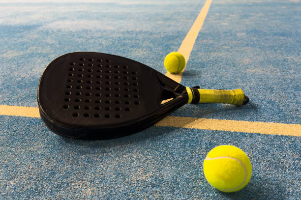 istock Black professional paddle tennis racket and ball with natural lighting on blue background. Horizontal sport theme poster, greeting cards, headers, website and app 2189152140