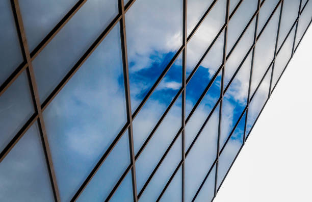 reflection of blue sky with white clouds in a window of a tall office building abstract architectural background