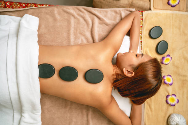istock woman is laying on a massage table with four black stones on her back 2189153502