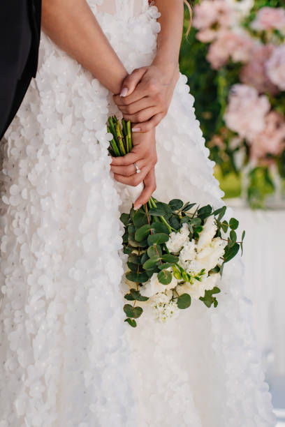 istock without a face. The bride is holding a delicate beautiful bouquet in her hands. 2189156207